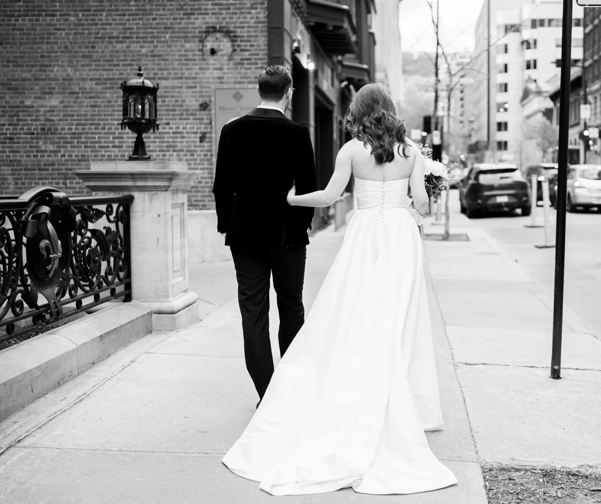 Mariés de dos, marchant dans une rue, photo en noir et blanc