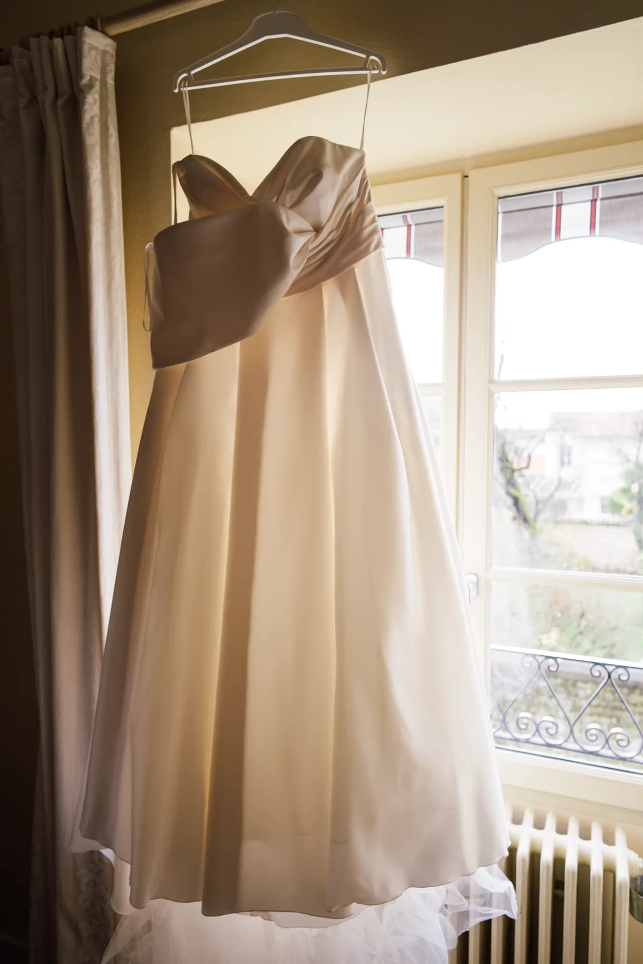 Robe de mariée suspendue devant une fenêtre
